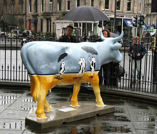 Fiberglass Cow Life Size Statue - Single Color 11 Painted cow sculpture with an artistic design featuring two smaller cows holding umbrellas.