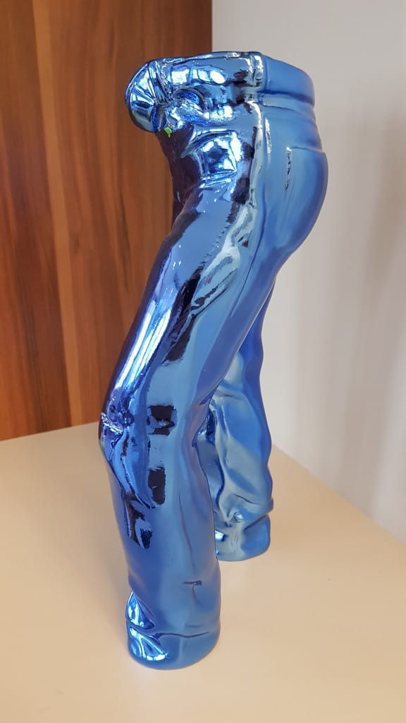 Small Decorative Jeans Resin Sculpture 3 Chrome blue sculpture of a pair of jeans positioned upright on a flat surface.