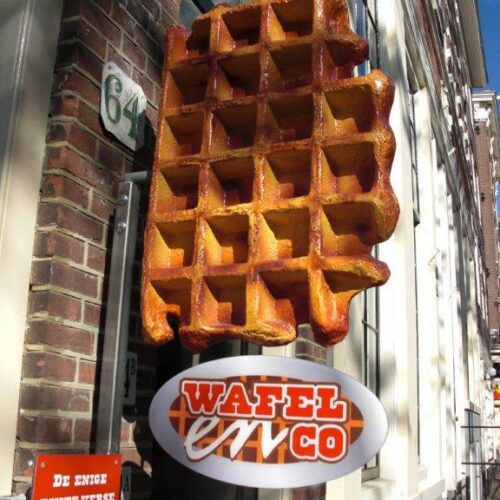 Large waffle sign hanging outside a brick building with the text