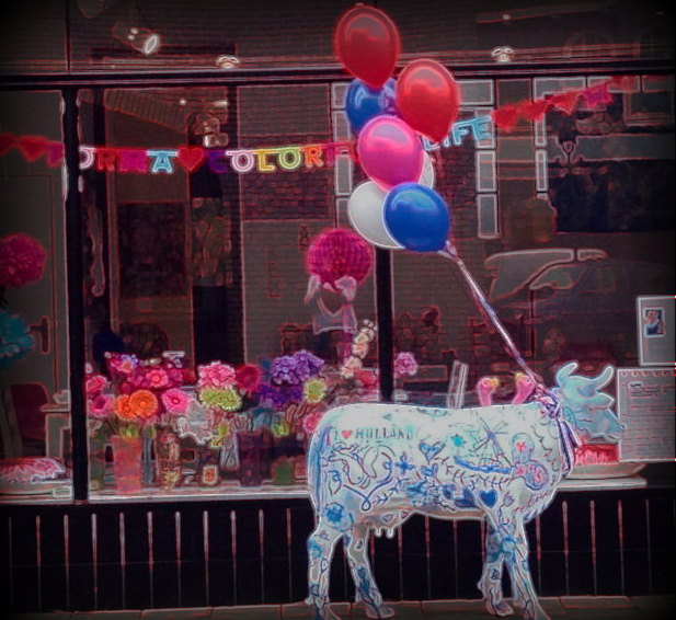 Fiberglass Cow Life Size Statue - Single Color 13 Colorful shop window display with a white cow statue covered in blue doodles, holding red, white, and blue balloons.