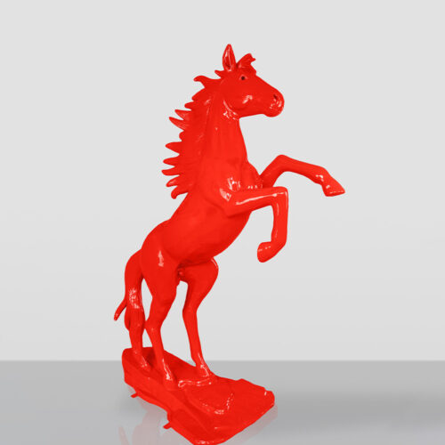 Glossy bright red sculpture of a horse rearing on its hind legs, standing on a rectangular base with a plain light gray background.