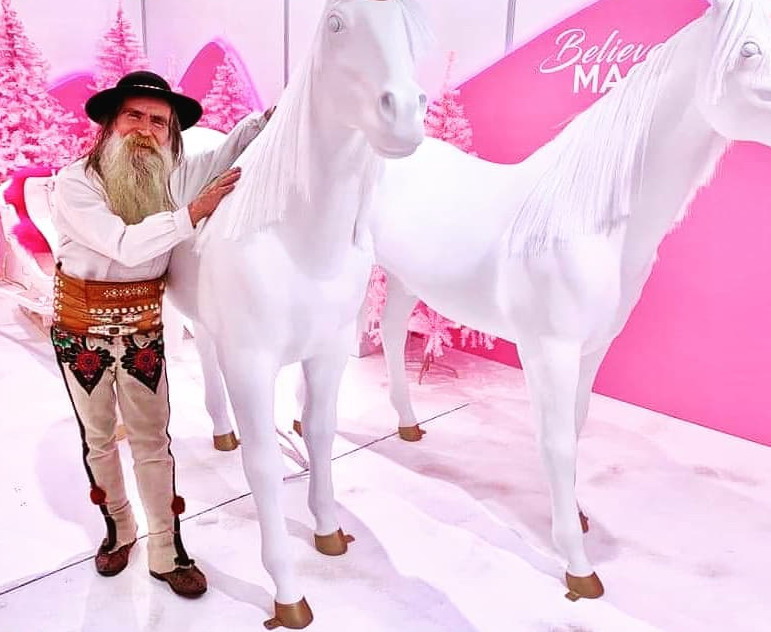 Fiberglass horse figure with a mane 2 A man in traditional attire stands next to two white horse statues in a pink-themed room with the phrase