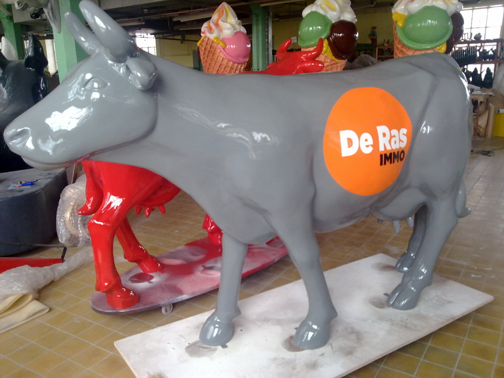 Fiberglass Cow Life Size Statue - Single Color 18 Gray cow statue with an orange circle on its side displaying the text