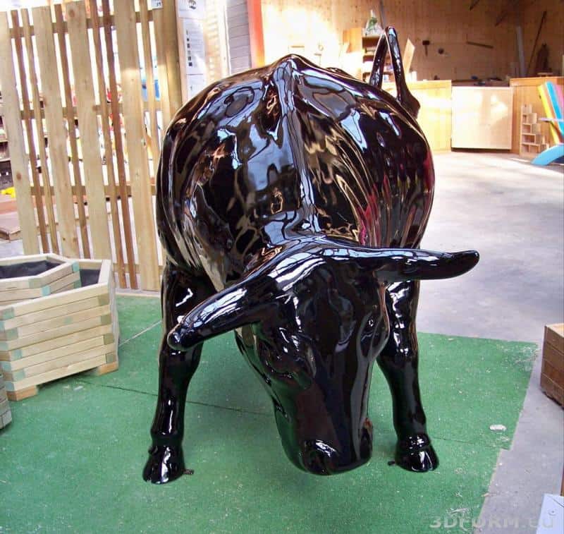 Large event bull figure 5 Czarna, błyszcząca rzeźba byka w pozycji pochylonej do przodu, umieszczona na zielonej sztucznej trawie w pomieszczeniu.