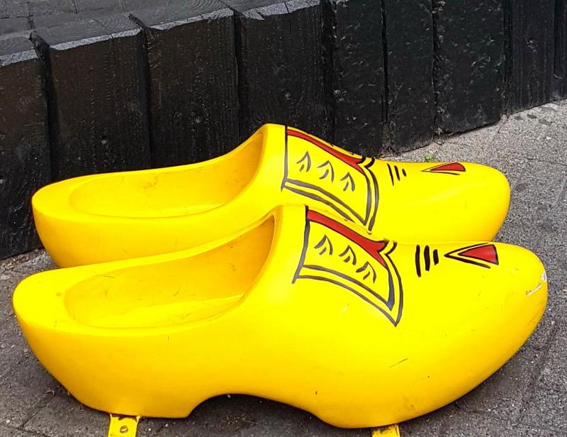 Żółte drewniaki z czerwono-czarnym wzorem, stojące na chodniku przy murze.