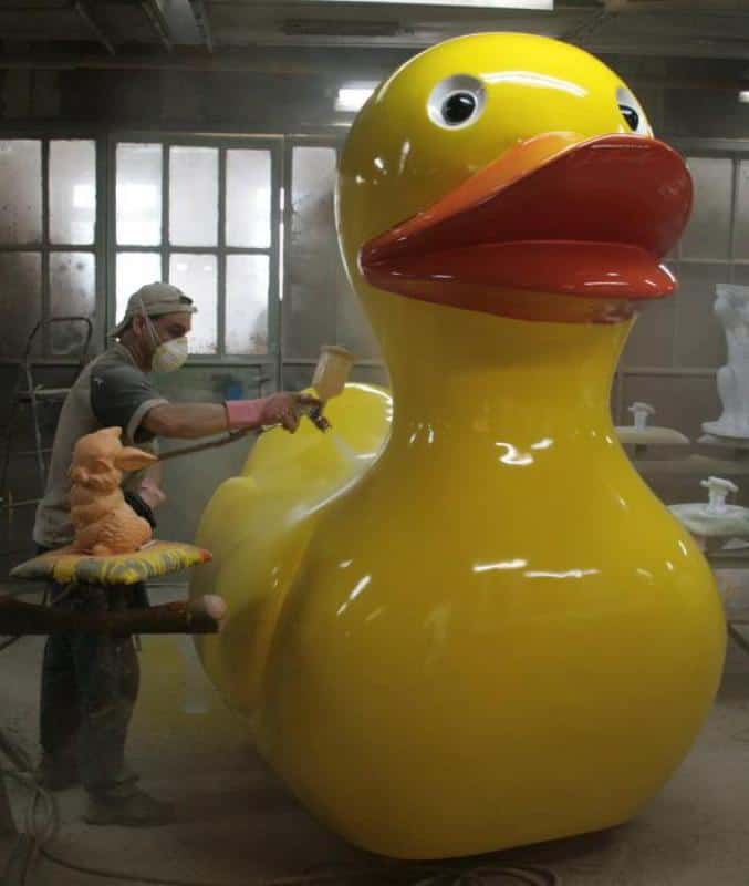Giant Duck 4 Mężczyzna maluje dużą figurkę żółtej kaczki.