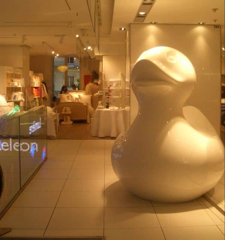 oryg_064490685_1129949550544944_1465385417682452480_o Large glossy white duck sculpture in a modern, well-lit store with home decor items on display.