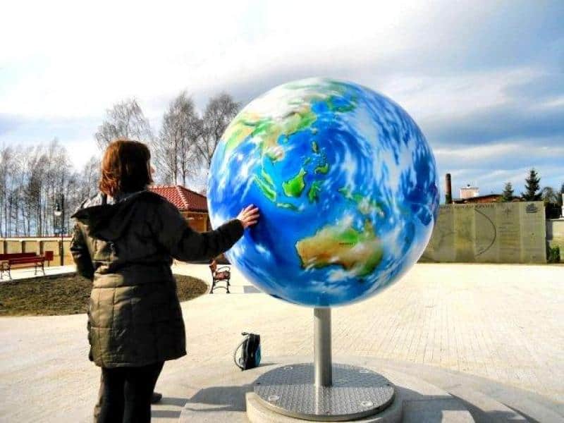 oryg_064490685_1129949550544944_1465385417682452480_o Person touching a large globe sculpture in an outdoor setting.