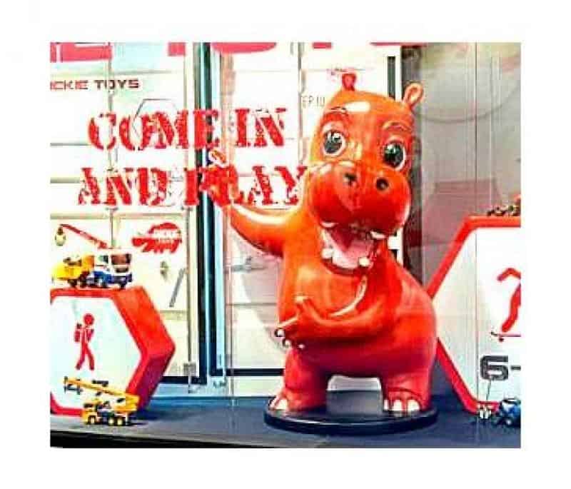 Advertising Hippo 2 Czerwona figurka hipopotama w witrynie sklepowej z napisem