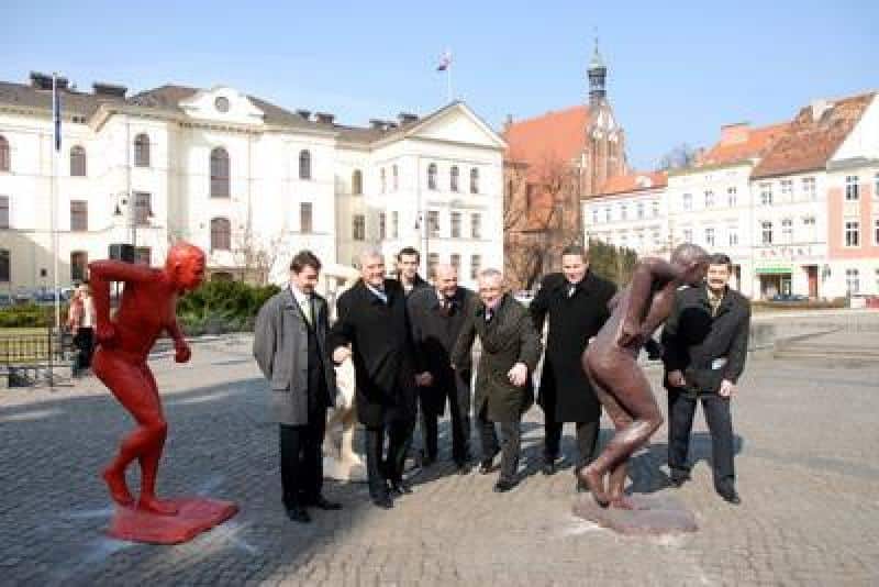 IAAF World Championships Promotion 3 Grupa mężczyzn na placu z rzeźbami w mieście z budynkami w tle.
