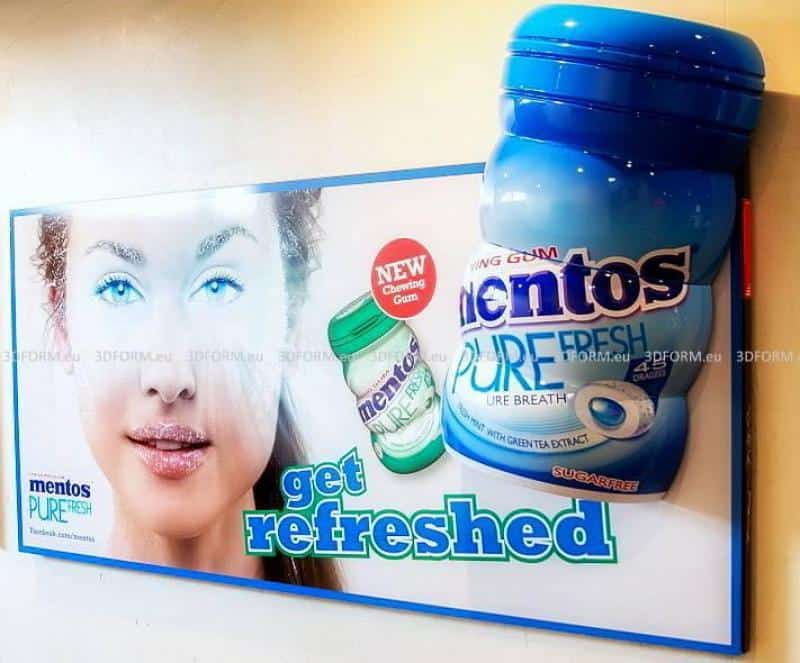 Mentos 3D billboard advertisement 1 Reklama gum do żucia Mentos Pure Fresh z twarzą kobiety i dużym opakowaniem gumy w tle. Napis