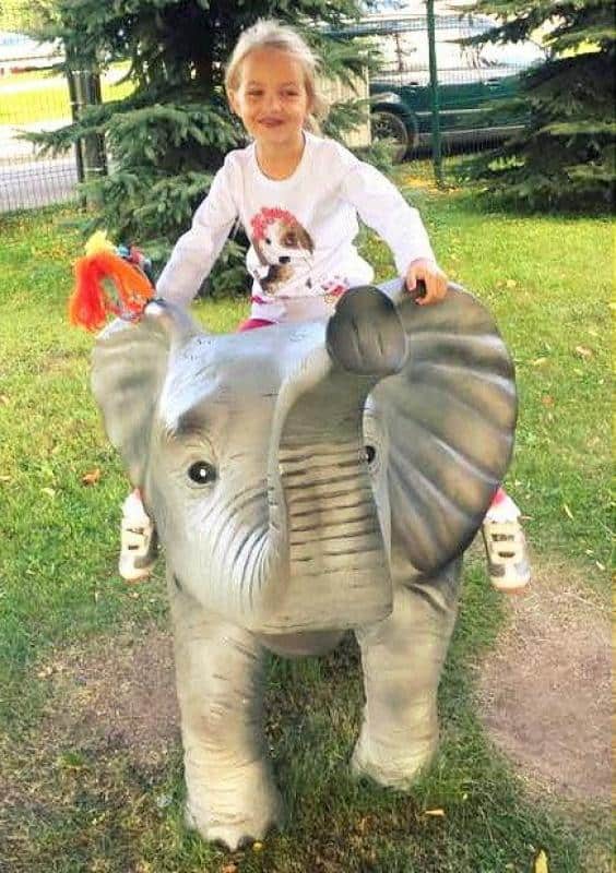 Figures in a theme park 5 Dziewczynka siedząca na figurce słonia na placu zabaw.