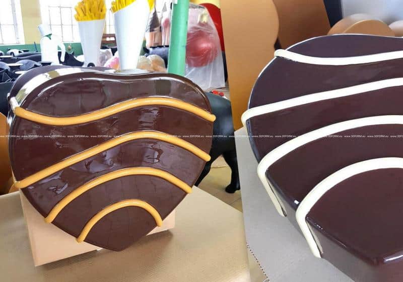 oryg_064490685_1129949550544944_1465385417682452480_o Two heart-shaped, brown glossy objects with wave-like ridges, one with yellow ridges and the other with white ridges, displayed in an indoor setting with various background objects.
