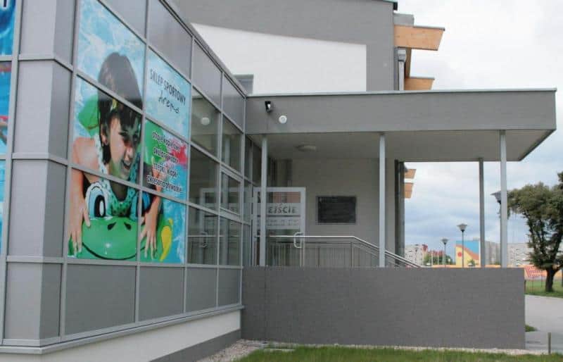 Decorative information board 3 Budynek z dużym plakatem przedstawiającym dziecko na dmuchanym materacu oraz wejściem z napisem