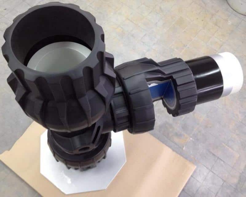 Tee - Pipe Fitting 4 Czarny element mechaniczny o skomplikowanej budowie, z przegubem i uchwytem, na tle kartonowej powierzchni.