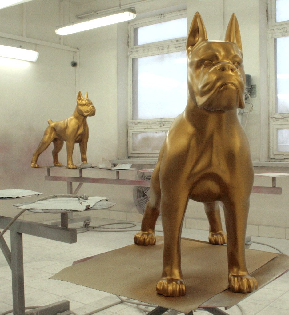 Boxer Dog Figure Standing - Single Color 3 Two large golden dog statues in a workshop with white walls and windows.