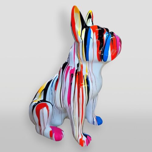 A colorful statue of a French Bulldog covered in vertical, dripping paint streaks in various colors, including red, yellow, pink, blue, black, and white. The background is plain and light gray.