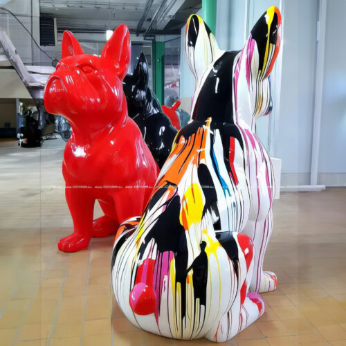 Large colorful statues of French Bulldogs, including a red one and a multicolored one, displayed indoors.