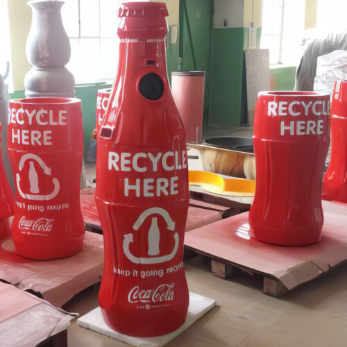 Several red recycling bins in the shape of Coca-Cola bottles with the message