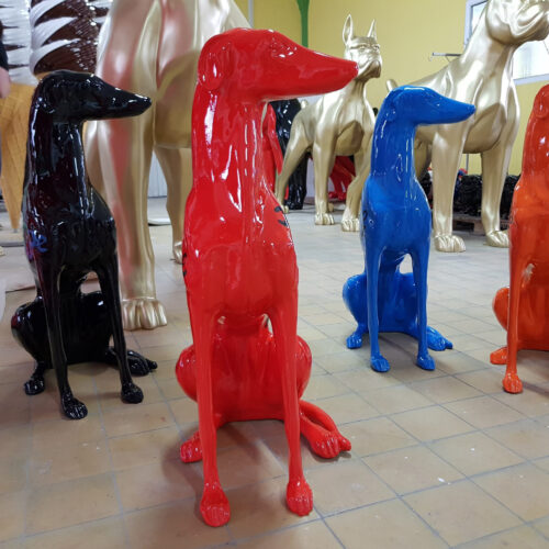 Colorful, glossy dog sculptures in blue, black, red, and gold on a tiled floor.