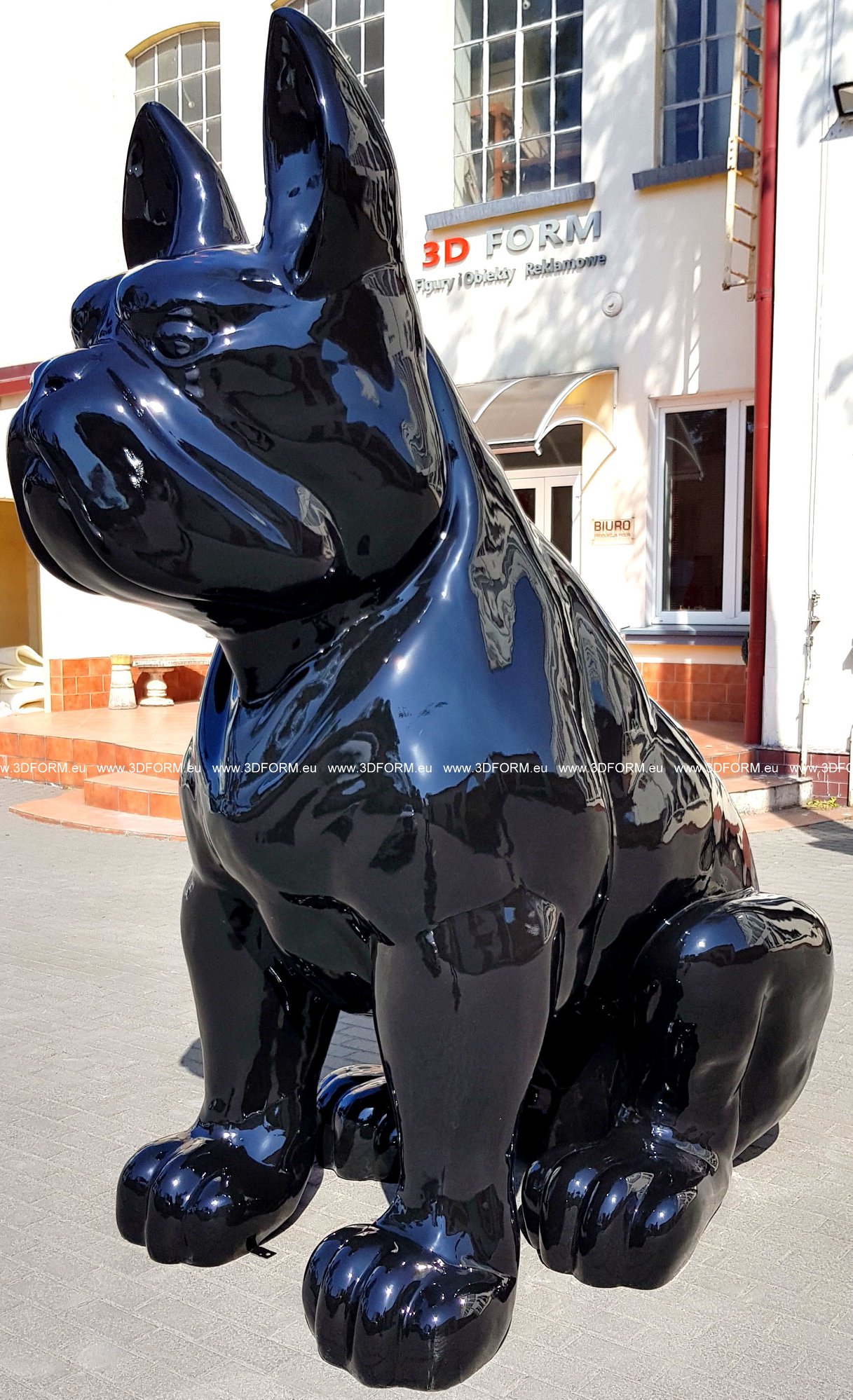 Giant sitting bulldog statue, single-colored. 5 Large black glossy sculpture of a bulldog in front of a building with