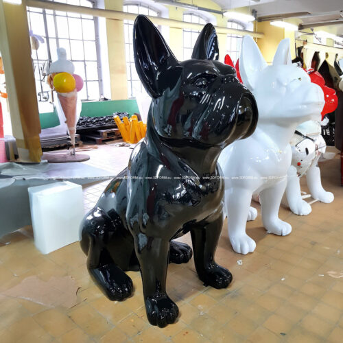 Large black and white glossy dog statues in an industrial workshop.