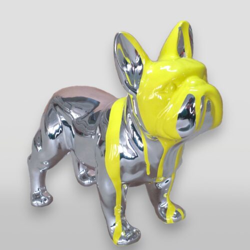 A chrome bulldog statue with yellow paint dripping over its head and body.