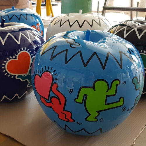 Large painted apples featuring colorful, abstract figures and heart designs.