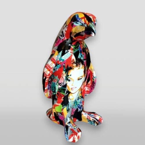 Multicolored penguin statue with collage-style artwork, featuring a woman's face and various abstract patterns.