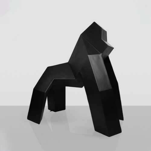 A modern black geometric sculpture of a gorilla, displayed on a reflective surface with a plain light grey background.