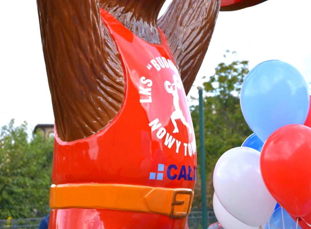 Posąg niedźwiedzia w czerwonym stroju sportowym z białym napisem 