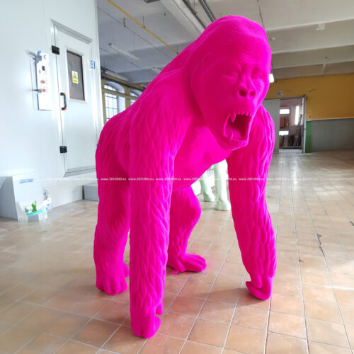 A large, bright pink gorilla sculpture standing on all fours in an indoor setting with tiled flooring.