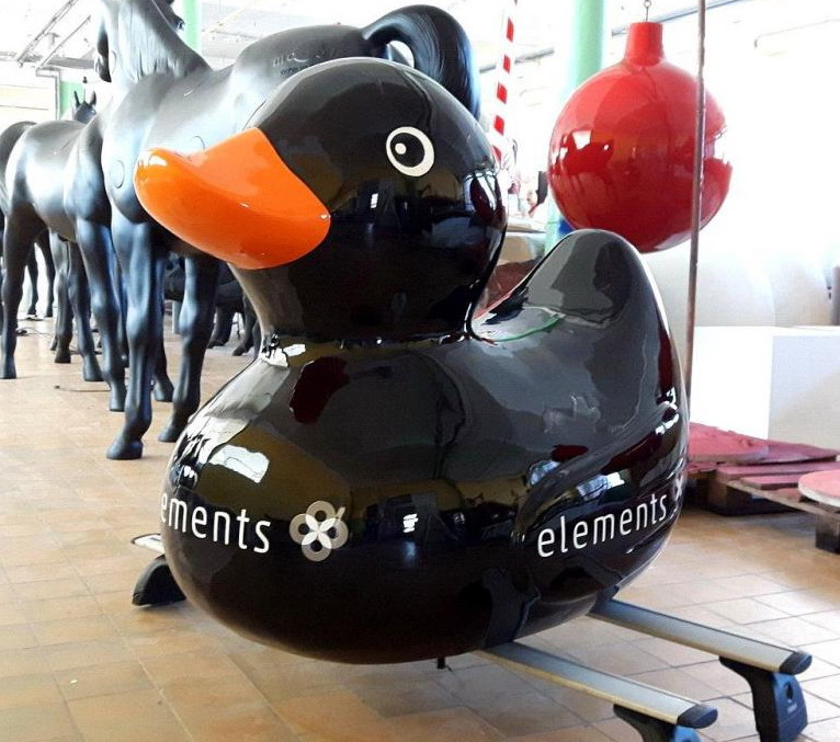 Decorative fiberglass duck statue 1 A large black rubber duck sculpture with an orange beak and the word