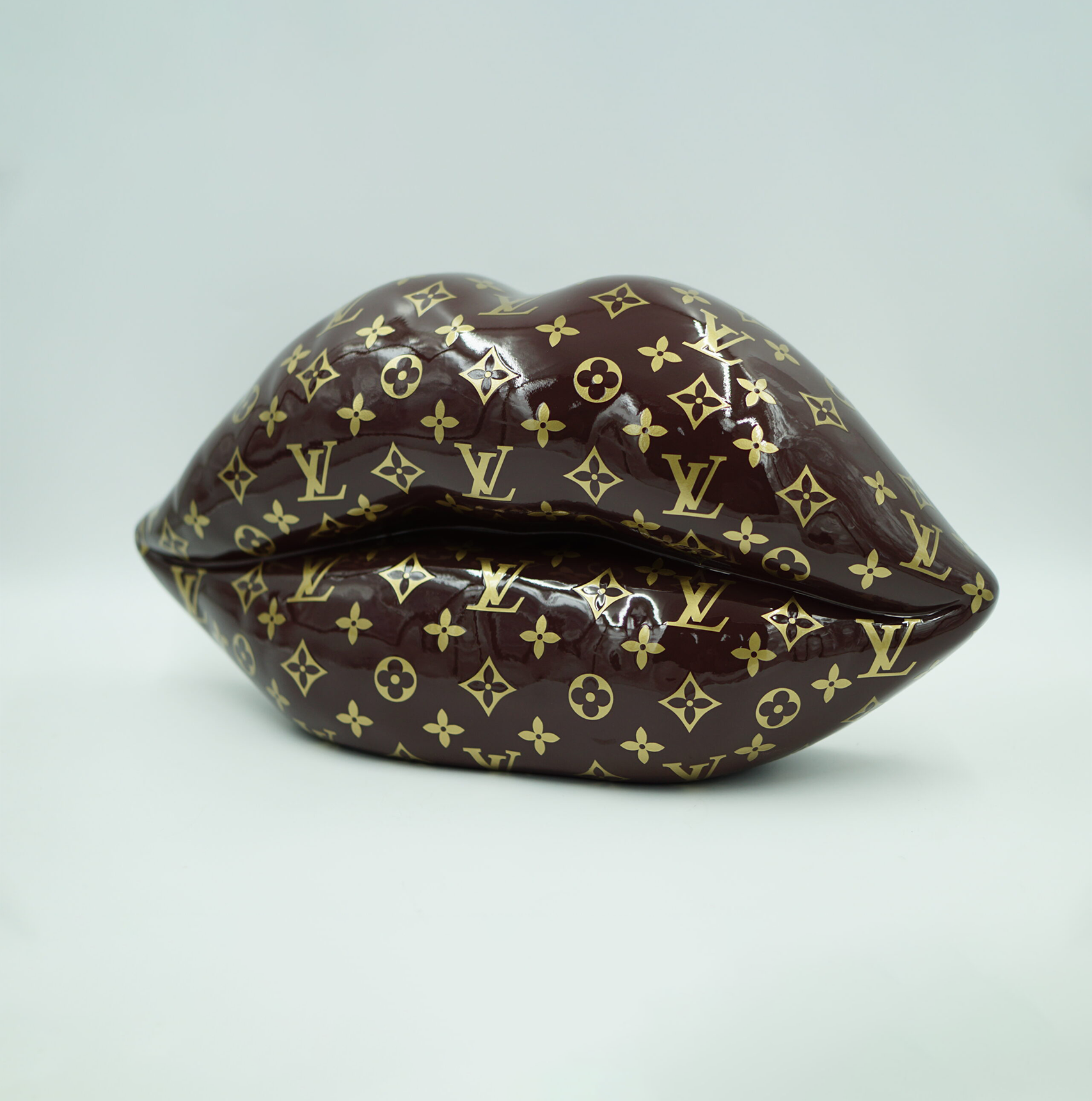 Brown lips with a golden monogram 1 Sculpture of lips covered in a brown and gold Louis Vuitton monogram pattern.