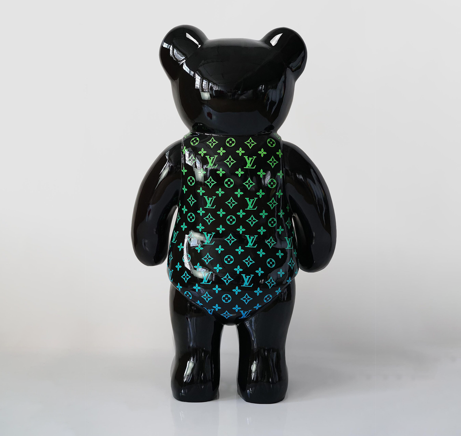 Teddy bear standing monogram - green gradient 2 Black bear-shaped figurine with multicolored Louis Vuitton monogram pattern.
