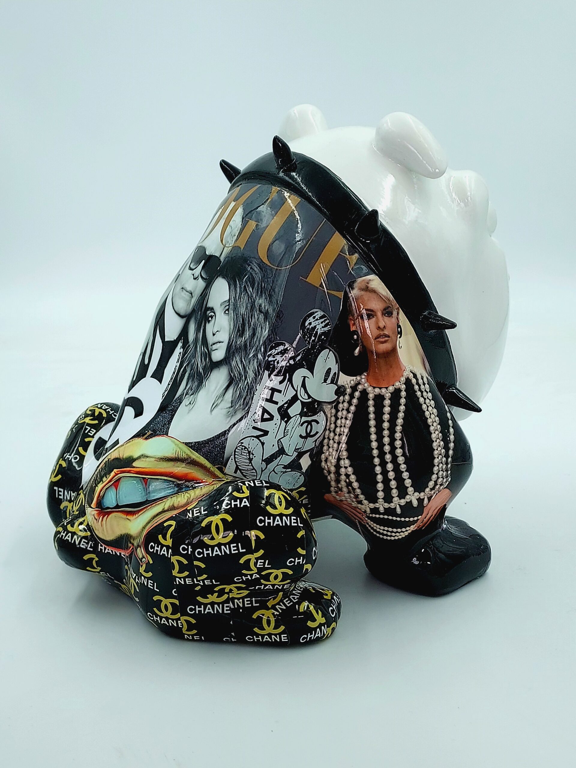 Bulldog Avella 55cm - Vogue 3 A white ceramic bulldog sculpture decorated with collaged images from fashion magazines, including recognizable logos like Chanel and Vogue, and a pair of prominent lips. The sculpture also features spiked details and various textures.
