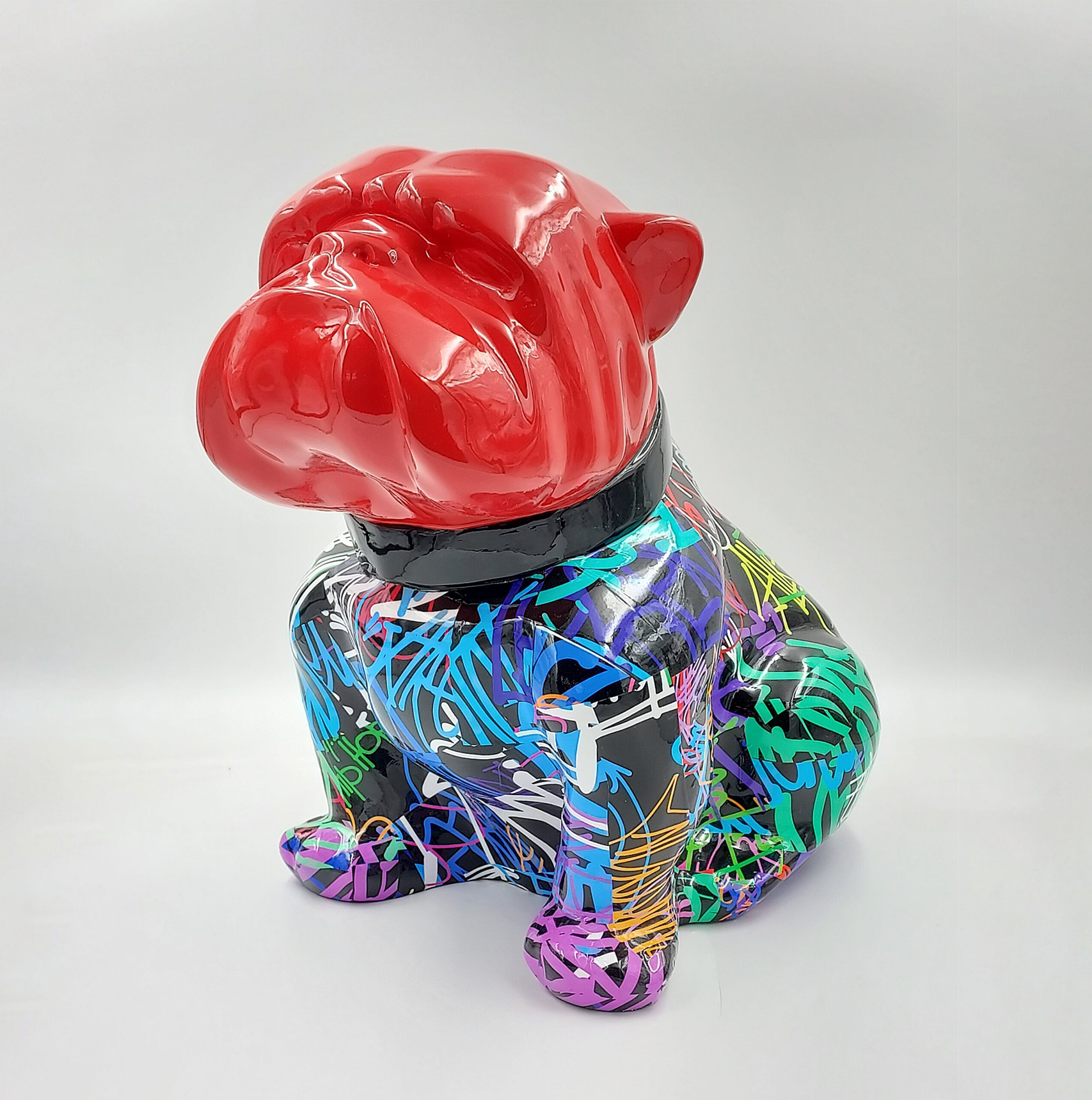 Bulldog Angelo 40cm dog - spray 1 A colorful bulldog statue with a red head and a body covered in vibrant graffiti-like patterns in blue, green, purple, yellow, and pink.