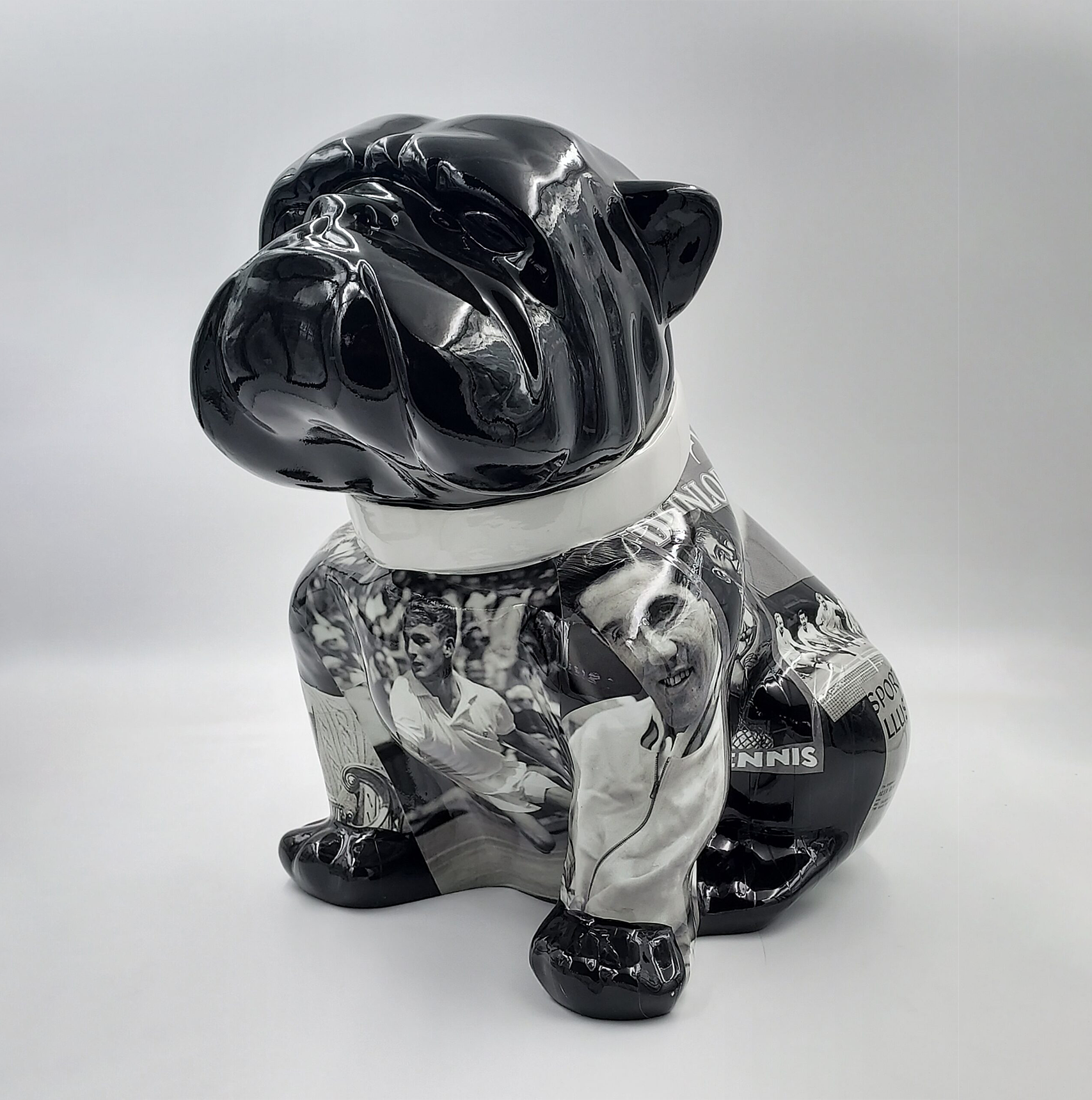 Bulldog Angelo 40cm dog - Tennis 1 Sculpture of a sitting bulldog with a shiny black head and collar, featuring a collage of black and white tennis-themed images on its body.