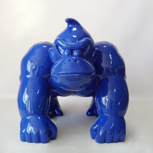 Blue glossy gorilla sculpture in a crouching position against a white background.