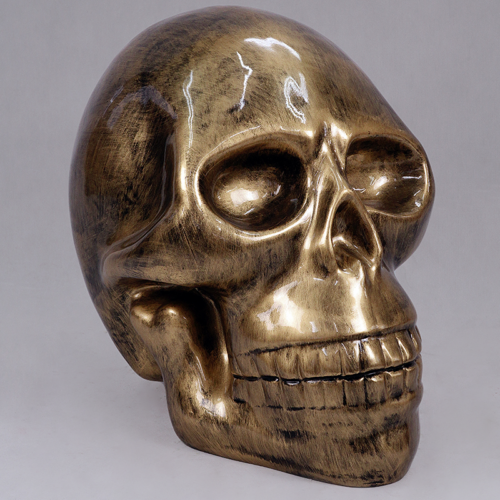 Gold, metallic skull sculpture with a reflective surface.