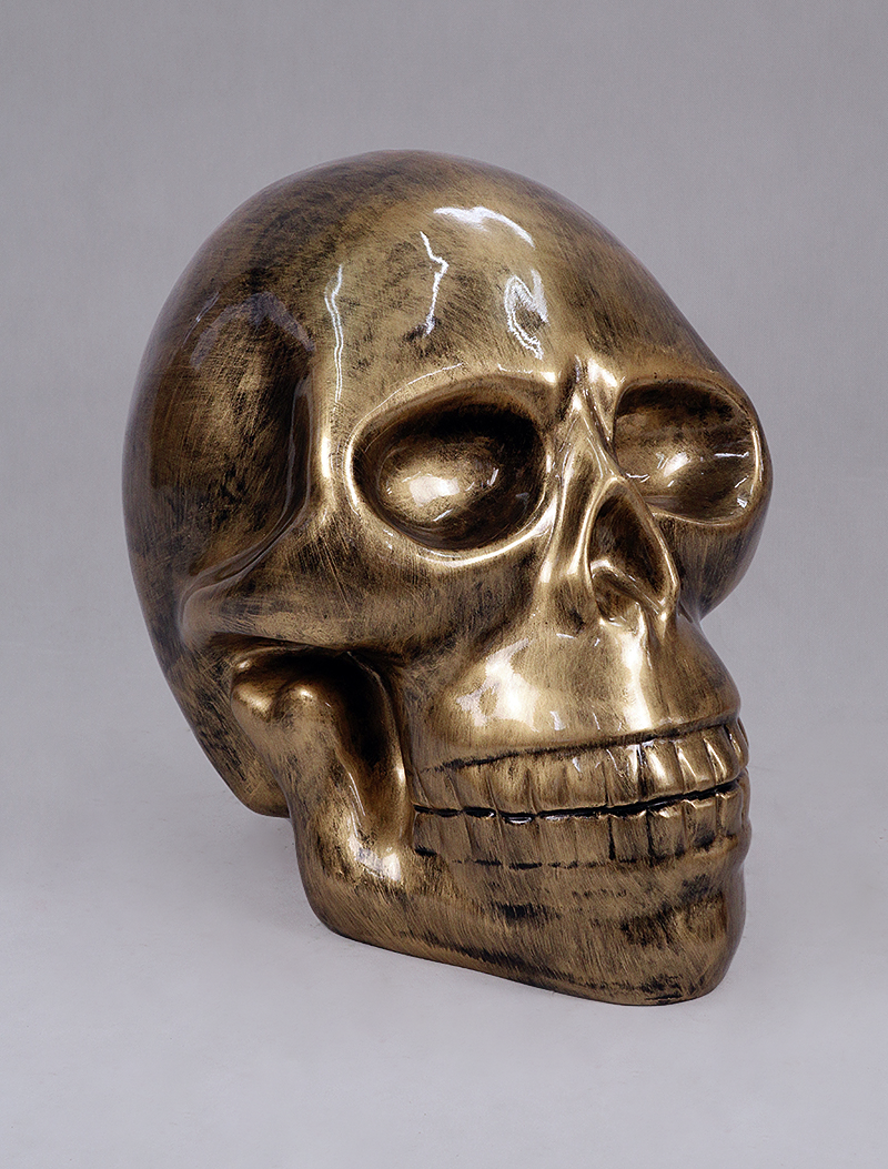 Skull - patina 1 Gold, metallic skull sculpture with a reflective surface.