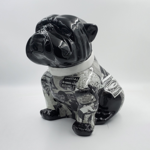 Black and white bulldog sculpture with a collage of vintage newspaper clippings covering its body.
