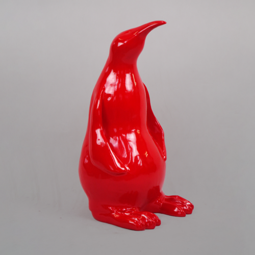 Red, glossy penguin statue on a gray background.