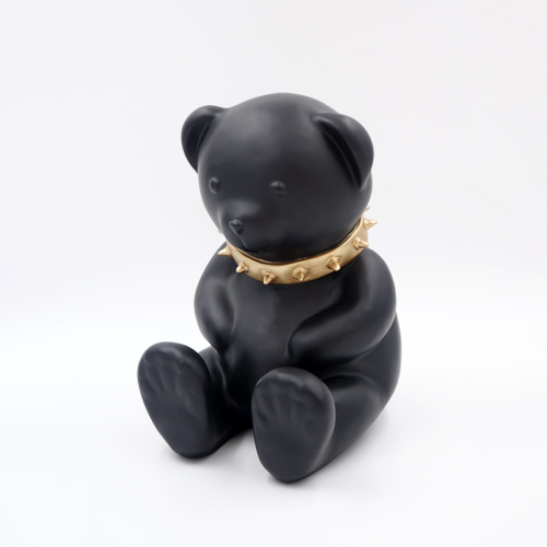 Black teddy bear figurine with a gold spiked collar.