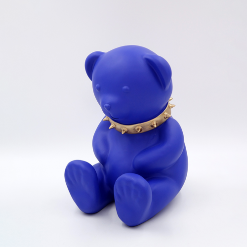 Blue teddy bear statue wearing a gold spiked collar.