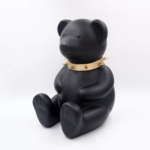 Black teddy bear figurine wearing a gold spiked collar.