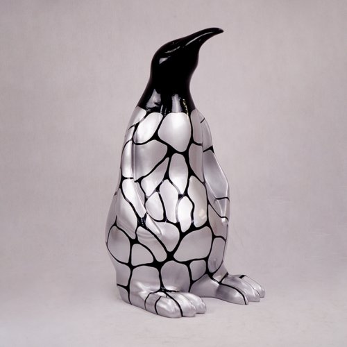Sculpture of a penguin with a shiny silver body and black geometric pattern.