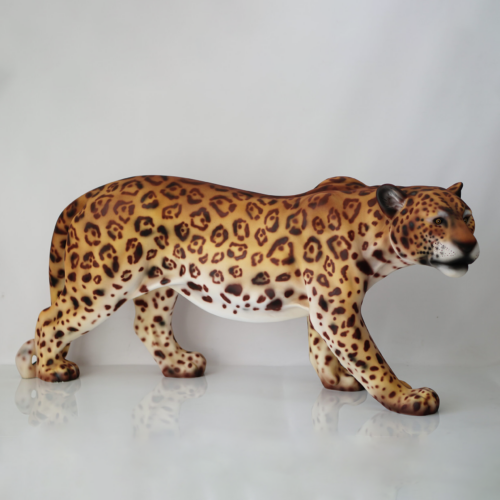 A lifelike sculpture of a leopard in a walking posture with detailed yellow and black spotted fur, displayed against a plain white background.