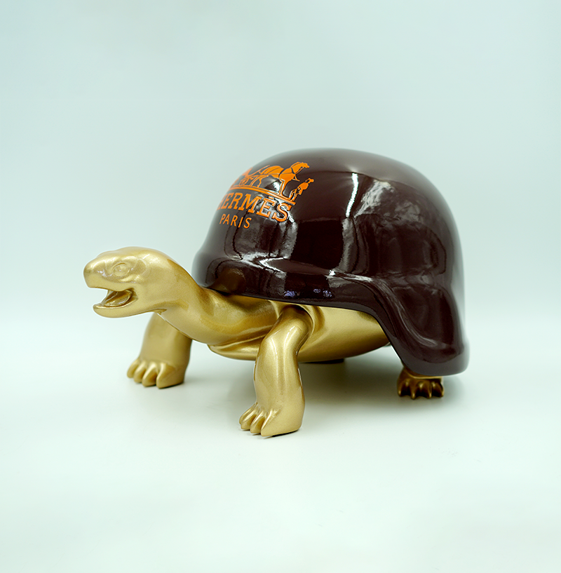 Turtle in a Helmet - H 2 Gold turtle sculpture with dark brown shell, featuring the Hermès Paris logo in orange on the shell.