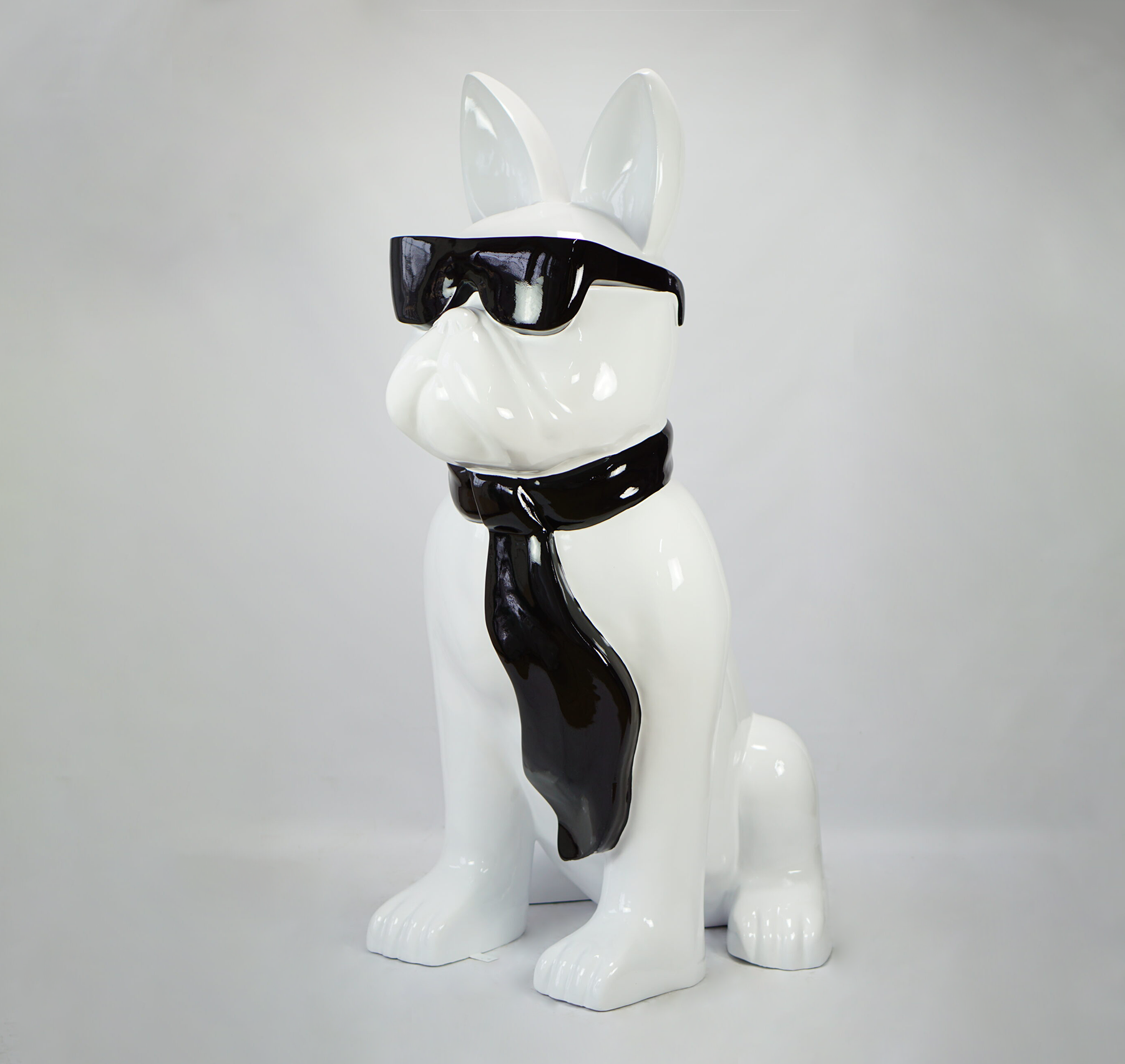 Large bulldog figure with tie and glasses - black and white 1 A white ceramic statue of a dog wearing black sunglasses and a black tie.